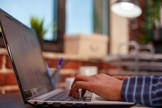 Selective focus of african american person typing on laptop, inputting project data at office desk. Closeup on hands of black male individual using digital device keyboard, searching on internet. photo