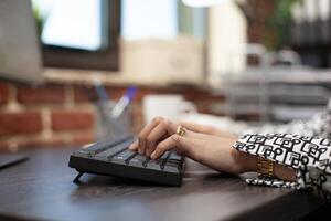 Female professional typing and inputting data, making updates to the company' project plan in modern workspace. Closeup view of an individual using office keyboard on a desk. photo