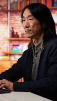 Vertical Portrait of smiling senior engineer coding advanced AI algorithm in startup office, refining machine learning models. Cheerful man using coding platform in Silicon Valley workplace, camera B video