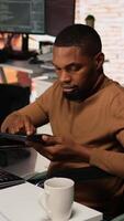 Vertical Admin in wheelchair using tablet in innovative startup office to build application. Inclusive software development agency worker with paraplegia checks code on device, camera A video