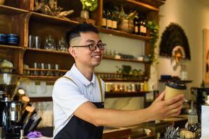 Vietnamese waiter holding paper cups with coffee in a cafe photo
