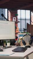 Vertical PC display on startup office desk showing programming languages written by programmers. Panning shot of computer in company workspace used for code testing and quality assurance video