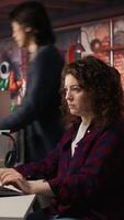 Vertical Smiling woman using programming languages on PC in IT startup office to build applications. Upbeat programmer using computer in software development agency to code, camera A video