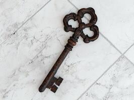 Rustic ornate key on a white tile background photo