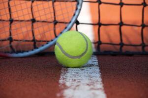 Tennis ball lying on the court next to a racket and the net photo