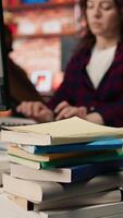 Vertical Close up of stacked books on startup office desk used by entrepreneur to study and learn how to grow business. Focus shot on pile of books used by venture company manager to do research, camera A video