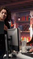 Vertical Startup intern holding laptop asks questions to senior technician coding advanced AI algorithm. Employee requests help from CTO manager in Silicon Valley workplace, camera B video