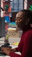 Vertical Silicon Valley venture programmer solving tasks with AI LLM chatbot using predictive technology. African american startup IT worker using PC to interact with generative model, camera A video