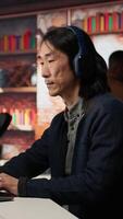 Vertical AI startup office chief technology officer listening music while coding application. Senior programmer wearing headphones while working in artificial intelligence software development agency, camera A video