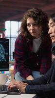 Vertical Coworkers collaborating in AI tech agency providing software development services. Teamworking startup office colleagues using artificial intelligence to streamline coding process, camera A video