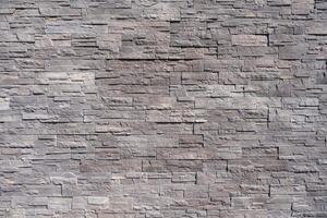 A detailed view of a modern gray stone wall with rectangular patterns and rough texture. photo