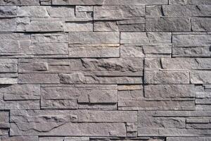 A close up detailed view of a modern gray stone wall with rectangular patterns and rough texture. photo