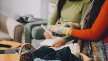 Two women are sitting in a room with a basket of clothes video