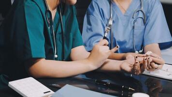 Two doctors are sitting at a table with a calculator video