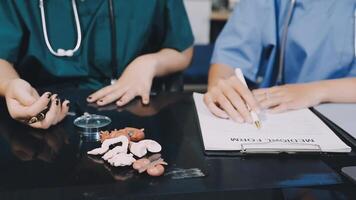 Two doctors are sitting at a table with a clipboard video