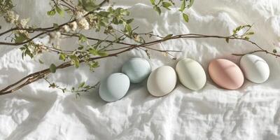 Row of pastel-colored easter eggs on white fabric with blooming branches photo