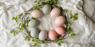Pastel-colored eggs in leafy wreath on fabric background creating a natural design photo