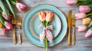 Elegant table setting with tulips and gold cutlery on rustic wooden surface photo