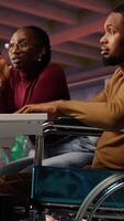 Vertical Manager coming to inclusive startup office employee in wheelchair desk to offer help. Thoughtful supervisor checking up on software development agency worker with disability, camera B video