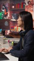 Vertical Startup intern holding laptop asks questions to senior technician coding advanced AI algorithm. Employee requests help from CTO manager in Silicon Valley workplace, camera A video