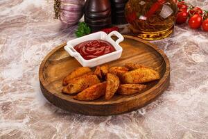 A wooden plate with some potatoes and ketchup photo
