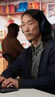 Vertical Senior admin coding advanced AI algorithm in startup office, refining machine learning models to enhance automation, wearing headphones. CTO manager listening music and coding, camera A video