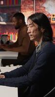 Vertical AI startup office chief technology officer drinking coffee and building application. Senior manager enjoying hot beverage while working in artificial intelligence software development agency, camera A video
