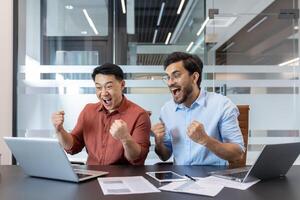 Two enthusiastic professionals celebrate a victory while working together in office. Their expressions convey excitement and teamwork, making it a dynamic and uplifting moment. photo