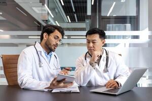 Doctors engaged in discussion over patient diagnosis in an office setting, utilizing tablet and laptop. Emphasizing teamwork, collaboration, healthcare, and technology. photo