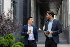 Two business colleagues walking down the street outside an office building, businessmen men in business attire talking and discussing, on a lunch break. photo