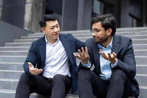 Supporting and comforting a partner, two men in business suits sitting on the stairs of an office building, a colleague helps a friend cope with frustration and anxiety. photo