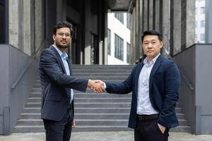 Two professionals engage in a business handshake outdoors, signifying agreement and collaboration. The image captures a moment of professional partnership in a contemporary setting photo