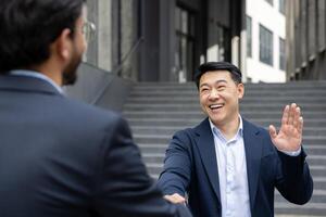 Two business professionals exchanging a friendly handshake and warm smile an outdoor urban setting. The scene captures the essence of professional courtesy, networking, and successful collaboration photo
