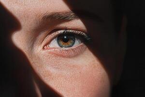 Half of a person's face is shrouded in deep shadows, highlighting one striking eye that looks intensely at the viewer, creating a powerful visual impact photo