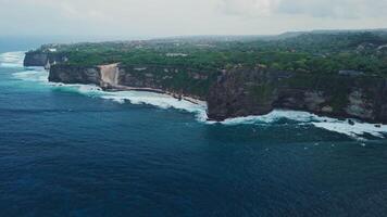 Rocky cliff coastline near Uluwatu temple in Bali. Drone view video