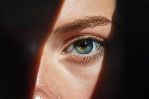 A striking close-up where intense blue-green eyes meet the viewer. The face is partially obscured by shadows, creating a sense of intrigue and depth in the expression photo