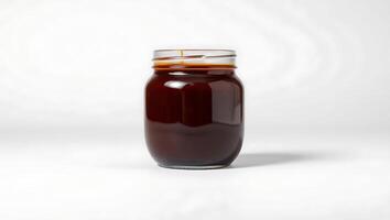 Dark liquid in a clear glass jar on a simple background photo