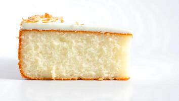 Slice of coconut cake on a light background with creamy frosting and toasted flakes photo