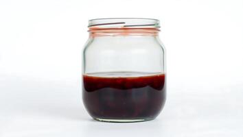 Dark syrup in a clear jar on a plain surface photo