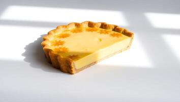 Bright slice of lemon tart on a smooth surface with sunlit patterns photo