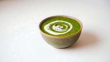 Fresh green soup with yogurt swirl in a simple bowl photo