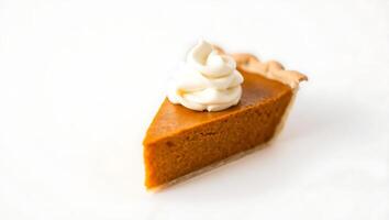 Slice of pumpkin pie topped with whipped cream on a plain surface photo