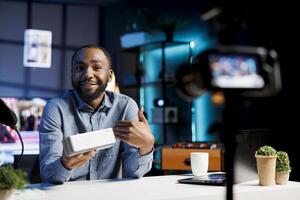 African american internet show host using professional camera and microphone to film content about best stereo audio devices of the year. Tech engineer recording Bluetooth speaker review photo