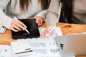 Two professionals working together using digital tablets and documents in a modern office environment. photo
