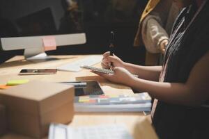 A person is writing on a piece of paper while sitting at a desk photo