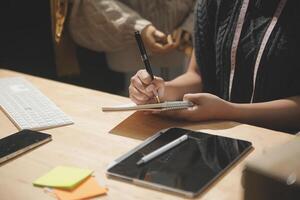 A woman writing in a notebook at a desk photo