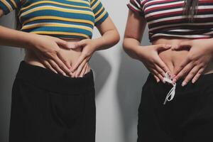 Two women with their hands on their stomachs photo