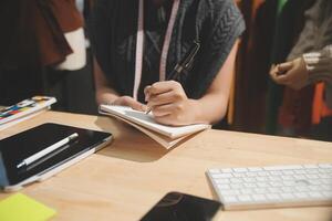 A person is writing in a notebook while sitting at a desk photo