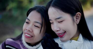 Handheld selective focus shot, Two Asian women in warm clothes standing and talking happily while enjoying the morning view with cold atmosphere. video