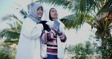 Handheld low angle view shot, Two women in warm clothing stand hugging each other and chatting happily while enjoying the view in the cold morning atmosphere. Winter Activities. video